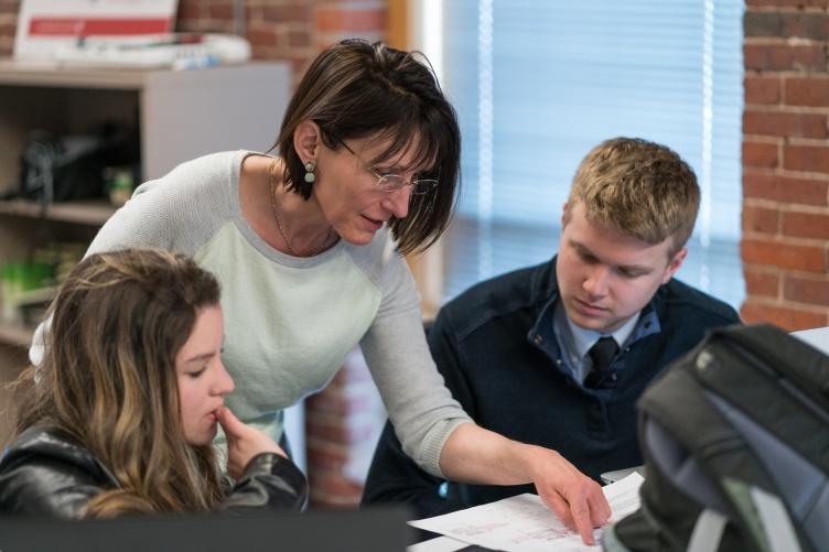 Female professor leans over two college students